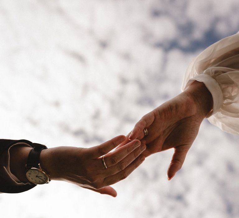 Brides reaching out to hold hands together with their new wedding bands 