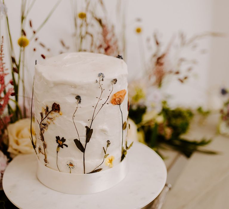 Single tier white iced rustic wedding cake with pressed wildflowers 