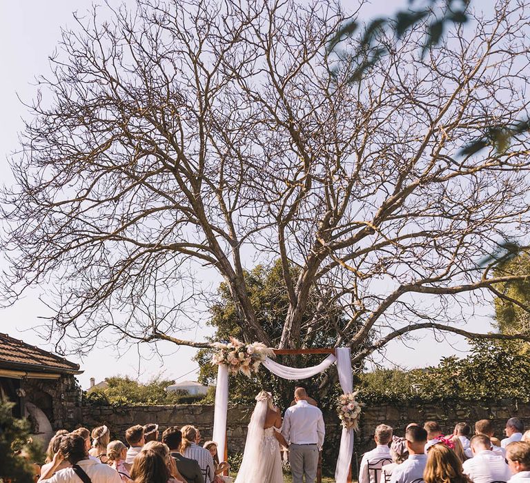 Outdoor wedding ceremony at destination wedding with white drapery on altar decoration 