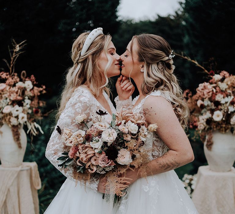 Garden wedding with two brides carrying autumnal bouquets with neutral flowers 