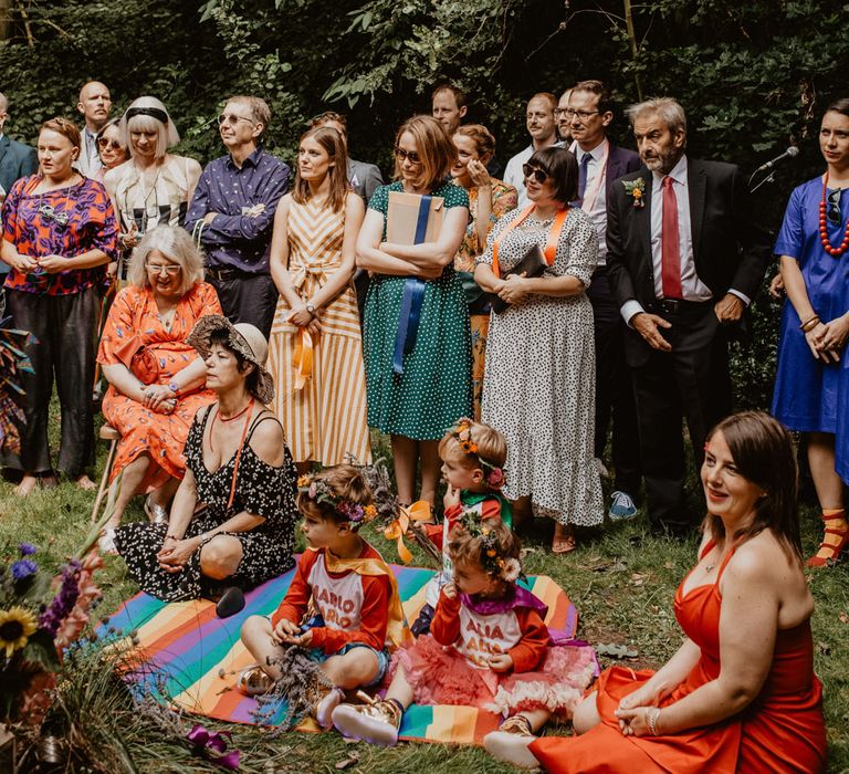 Wedding guests at outdoor wedding ceremony with rainbow wedding decor 