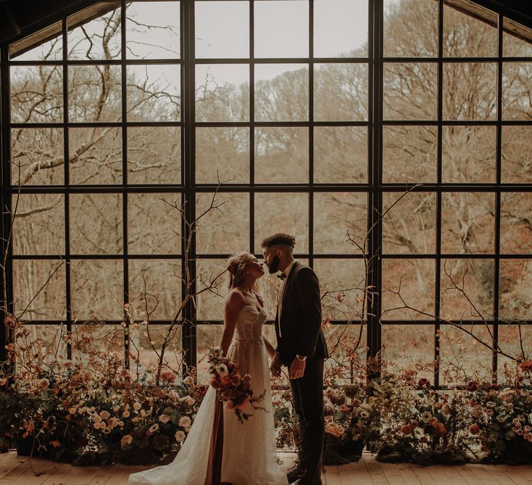 Bride and groom standing in front of the Crittal windows at Hidden River Cabins