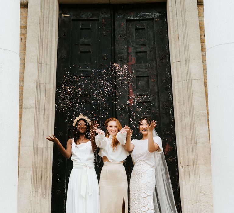 Brides in casual wedding dresses and two pieces throwing confetti outside The Asylum chapel 