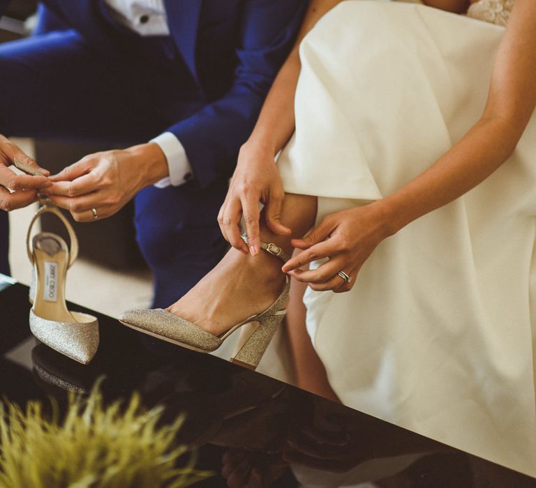 Bride putting on her gold Jimmy Choo's