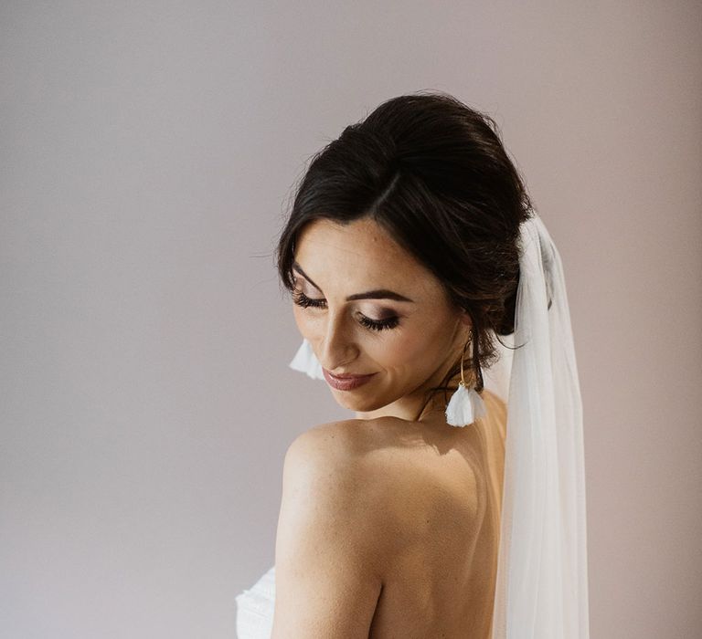 Smiling bride looks down over her shoulder in strapless wedding dress