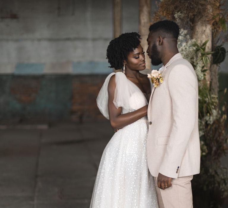 Black bride and groom in a sequin wedding dress and beige suit at industrial wedding 