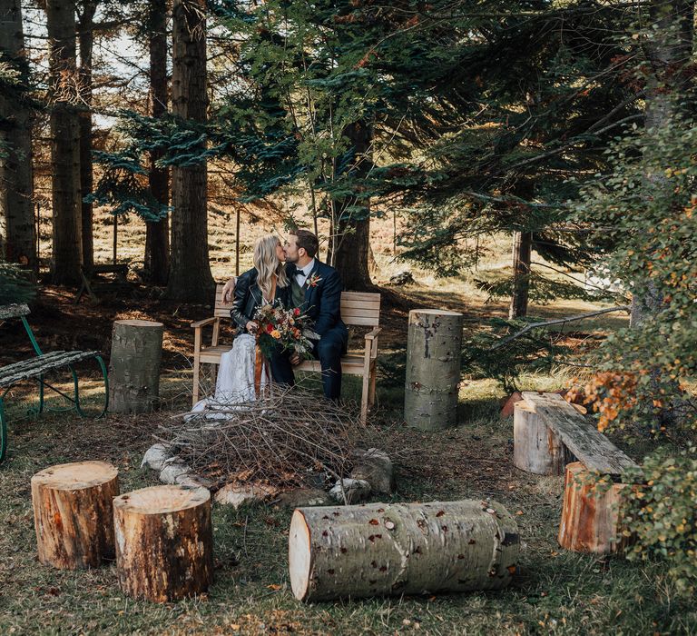 Woodland ceremony setup with tree trunks and wooden bench 