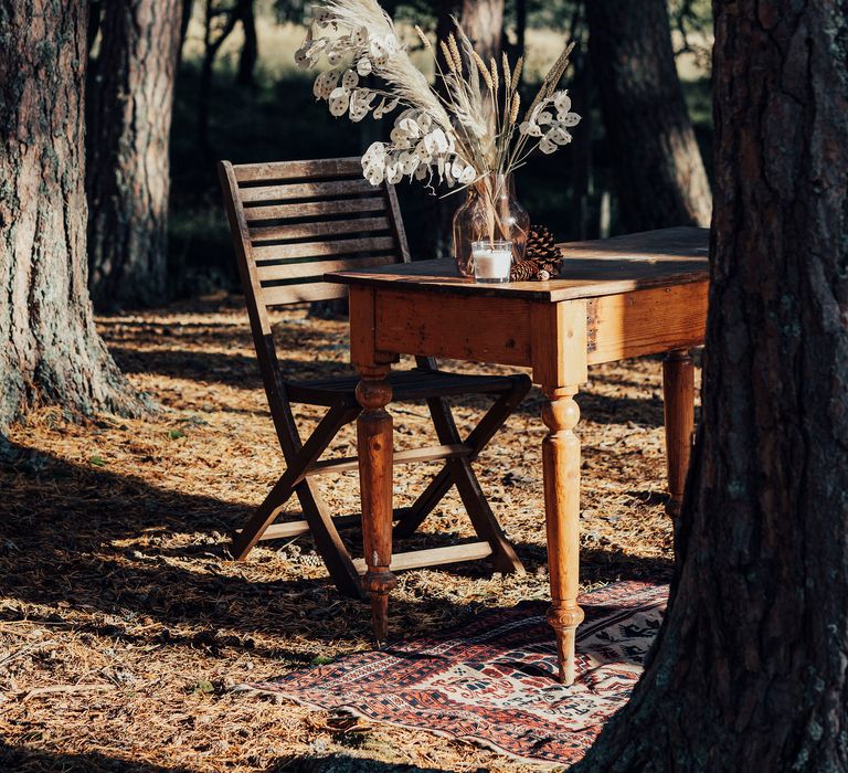 Wooden table outdoors with vases filled with dried flowers