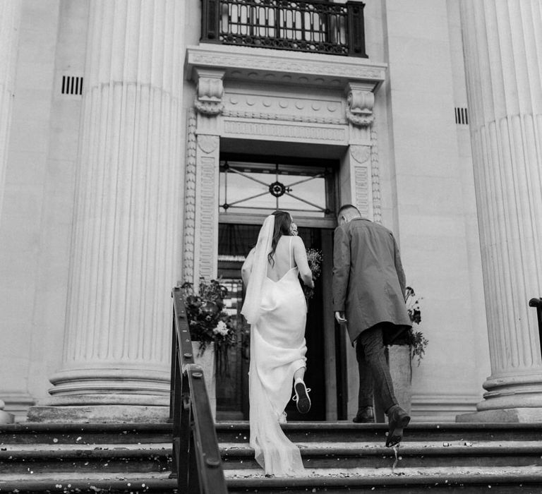 Bride and groom walking up stairs to their wedding venue