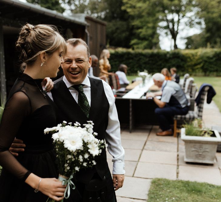 Bride wears long sleeved black dress with white bouquet 