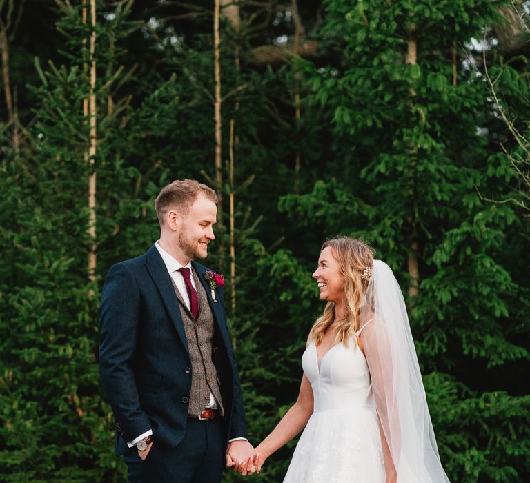 Bride & groom look lovingly at one another whilst holding hands