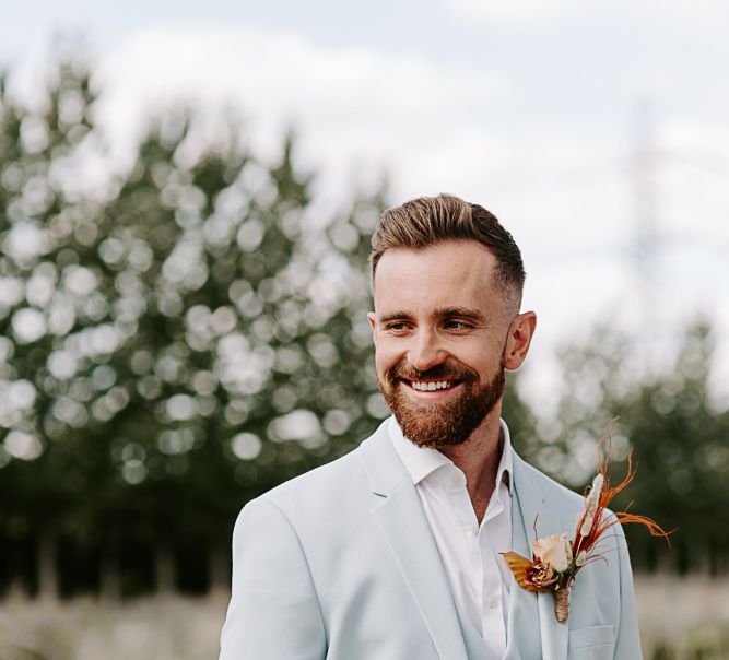 Groom wears pastel blue suit with eye-catching buttonhole floral detailing