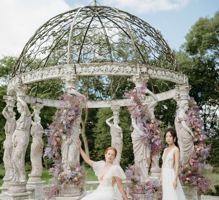 Brides stand together outside bandstand surrounded by lilac florals in the Spring