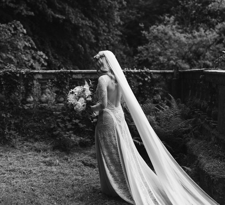 Bride in Grace Loves Lace wedding dress and single tier cathedral length veil holds pink and white rose bouquet in the gardens at Drenagh Estate Wedding