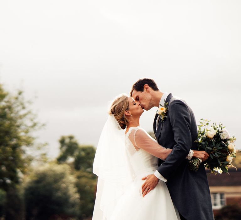 Bride & groom kiss during wedding day outdoors