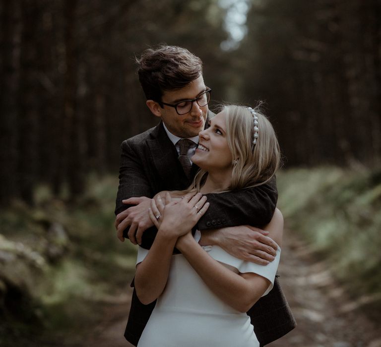 Groom embraces bride outdoors on the morning of their wedding