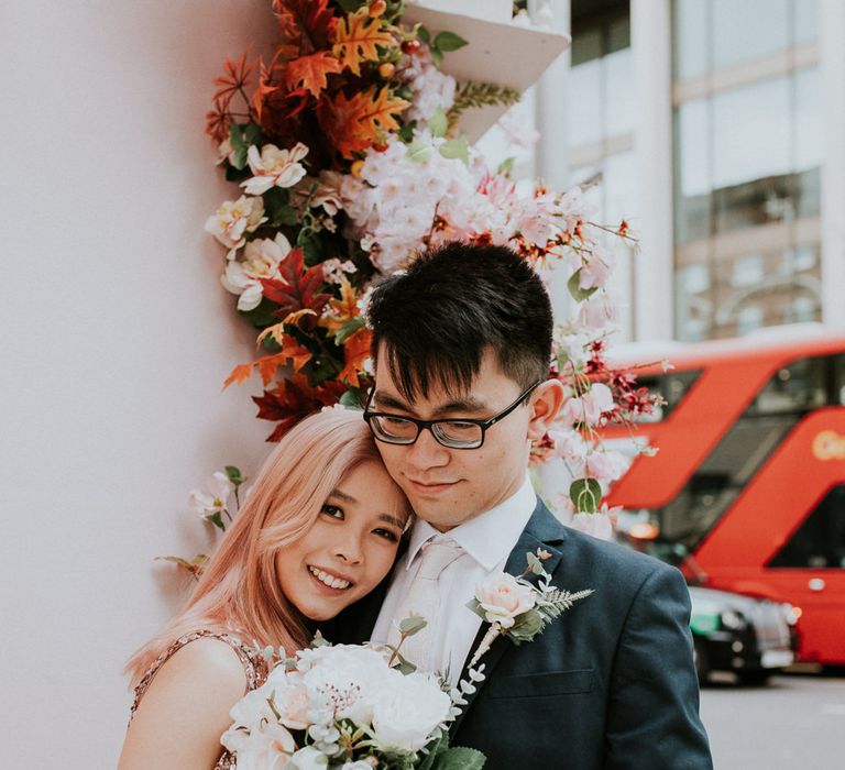 Intimate bride and groom wedding portrait with bride in a sparkly dress holding a pink and white rose bouquet 