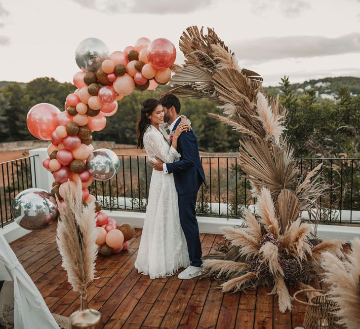 Coral balloons and dried palm leaf arch 