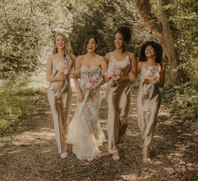 Bridal party portrait with the bride in a lace dress and the bridesmaids in full length satin dresses 