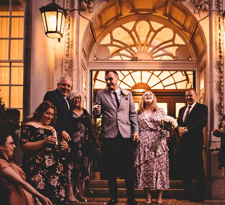 Bride laughs as she holds hands with her groom on steps after marrying at Chelsea Old Town Hall