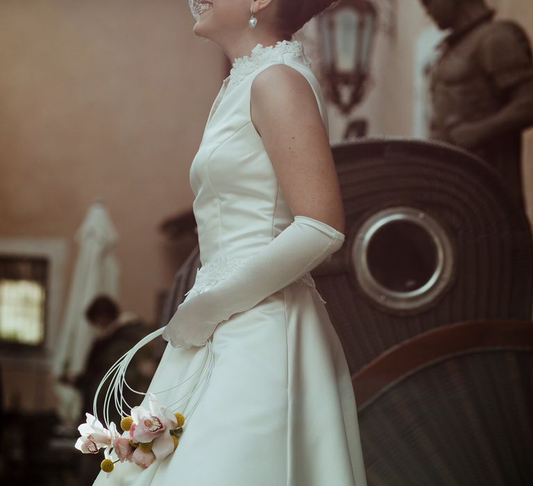 The bride wore a sleeveless vintage style wedding dress with a netted veil and white bridal gloves