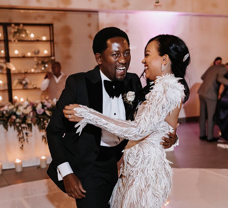 Bride and groom laughing on the dance floor with the bride in a strapless Biji La Maison de Couture wedding dress with detachable sleeve detail