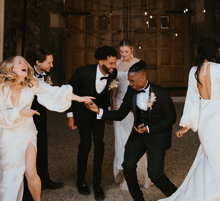 Wedding party portrait with bridesmaids and groomsmen in horseshoe waistcoats laughing 