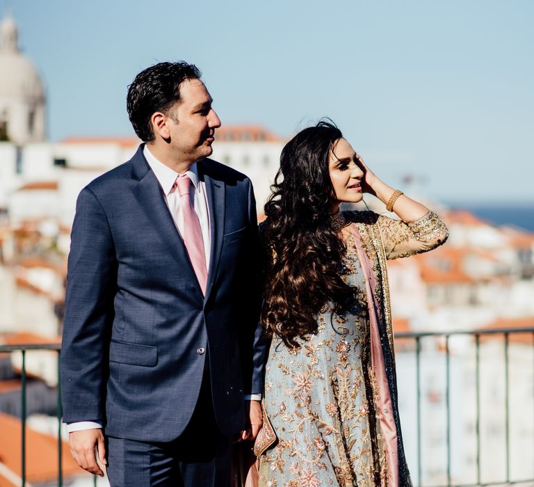 Bride & groom look across Lisbon, as groom wears blue suit with pink tie 