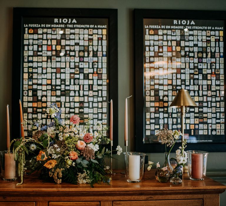 Interior of the Hotel du Vin Harrogate for wedding breakfast with framed Rioja label prints, white and orange candles and multicoloured florals