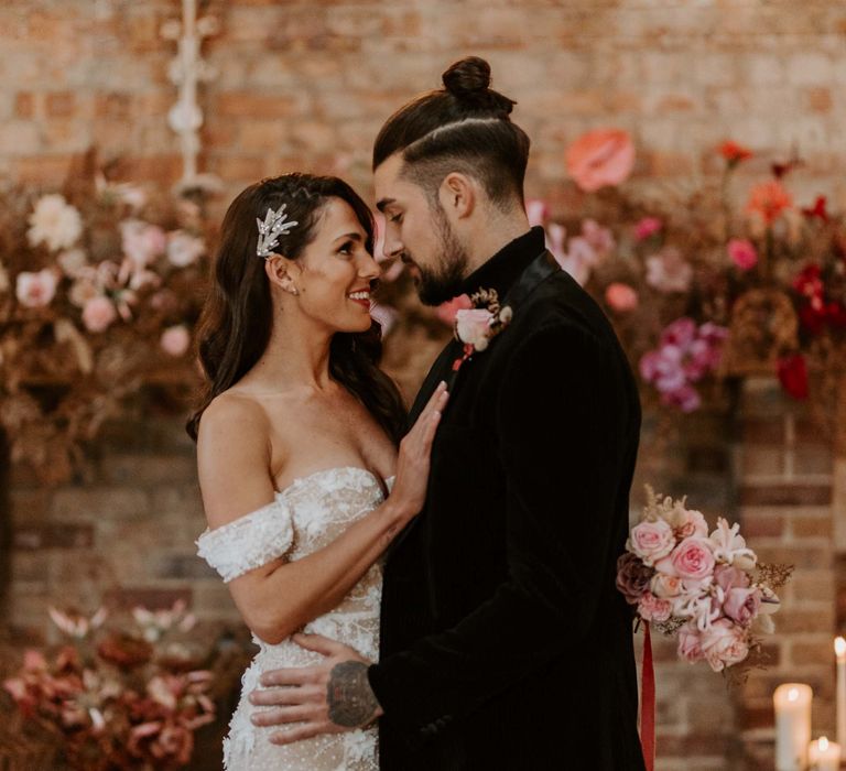 Stylish bride and groom standing at the altar of Botley Hill Barn in a black suit and strapless wedding dress with side swept hair 