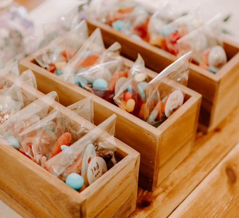 Colourful wedding favour sweets in plastic bags placed within wooden boxes