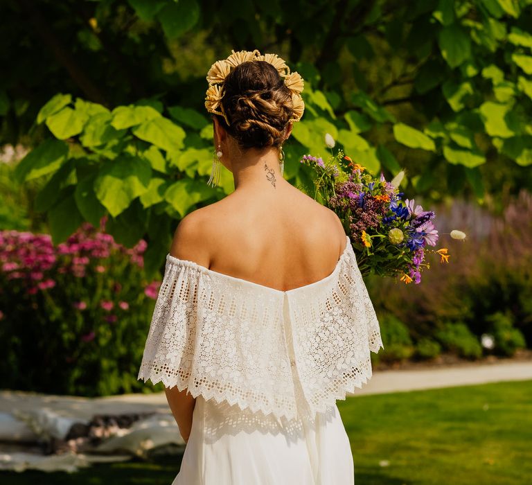 Bride in a strapless wedding dress with lace overlay holding a wildflower bouquet and wearing a yellow appliqué headband 