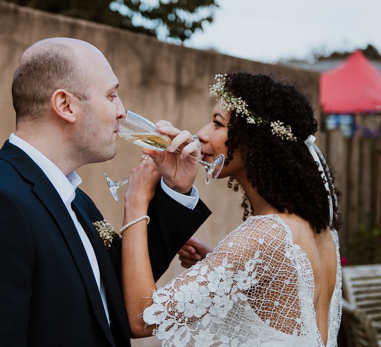 Bride & groom sip champagne together on their wedding day as they look lovingly at one another