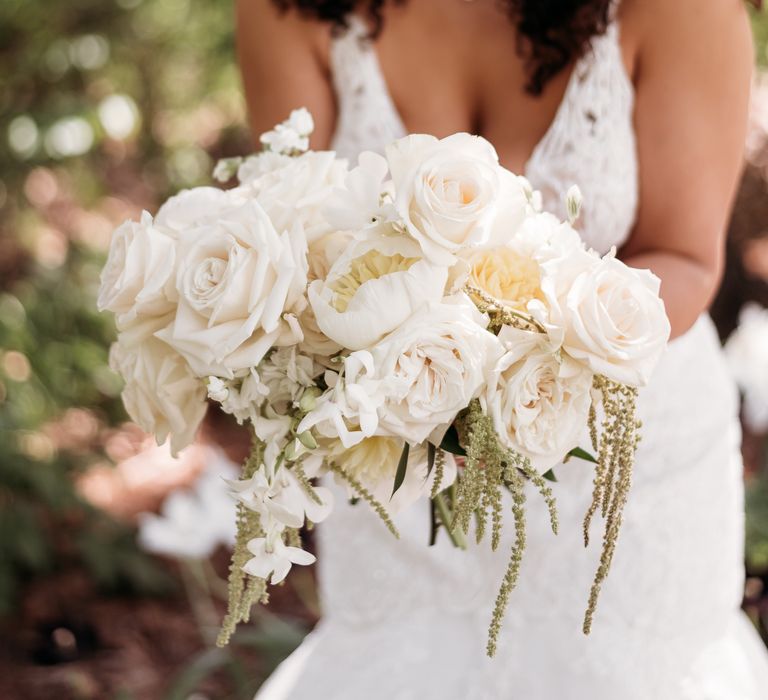 Bride shows off her classic white floral bouquet filled with roses and peonies