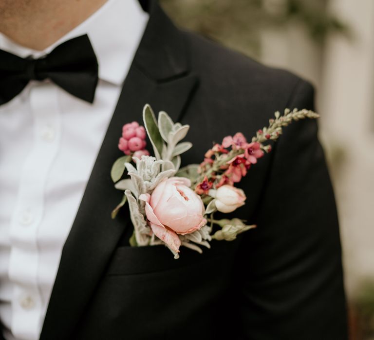 Groom in a black tuxedo with a pink rose buttonhole flower 