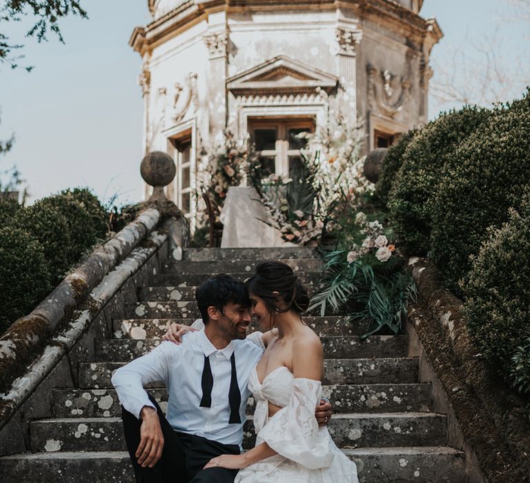 Bride in a strapless wedding dress sitting on the steps at The Larmer Tree gardens 