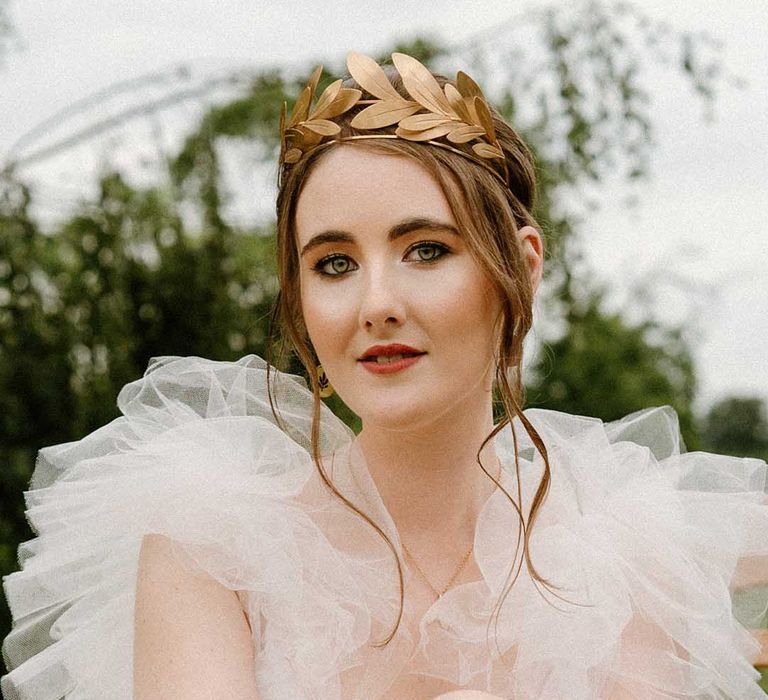 Beautiful bride with natural makeup in a tulle wedding dress wearing a gold laurel crown headdress