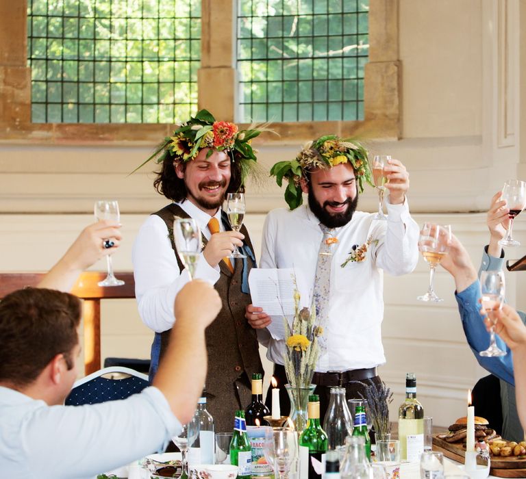 Grooms cheers on their wedding day as wedding guests lift their champagne glasses