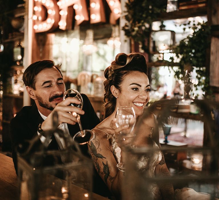 Bride and groom smile as they hold wine glasses on their wedding day