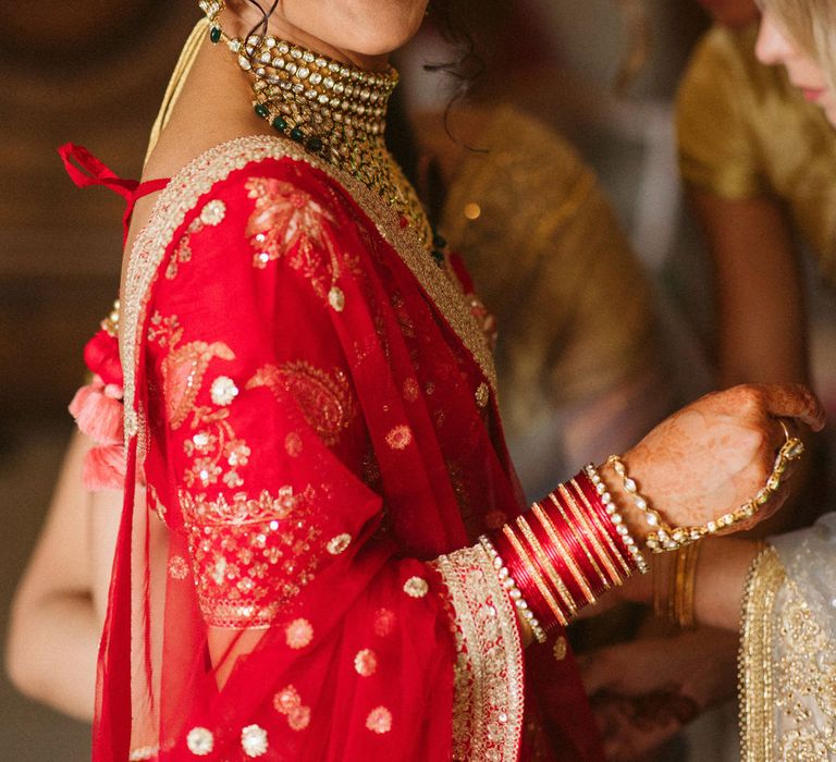 East Asian bride in a red and gold sari with red lipstick and gold Indian jewellery 