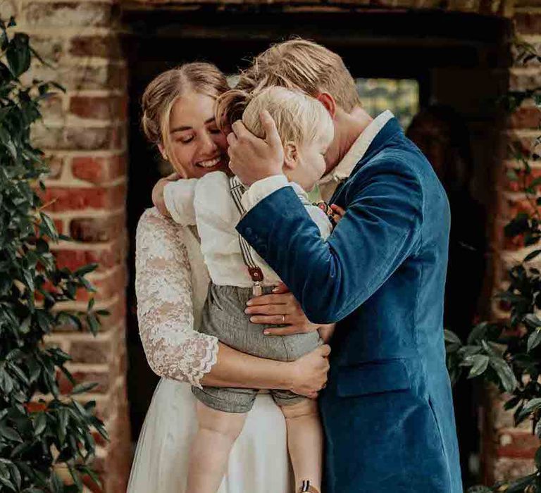 Bride and groom cuddle their son on their wedding day