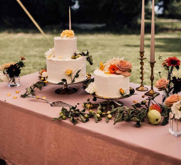 Dusky pink wedding table with white cake wedding cakes with floral decor, pink dinner candles and assorted foliage for marquee wedding reception in Cornwall