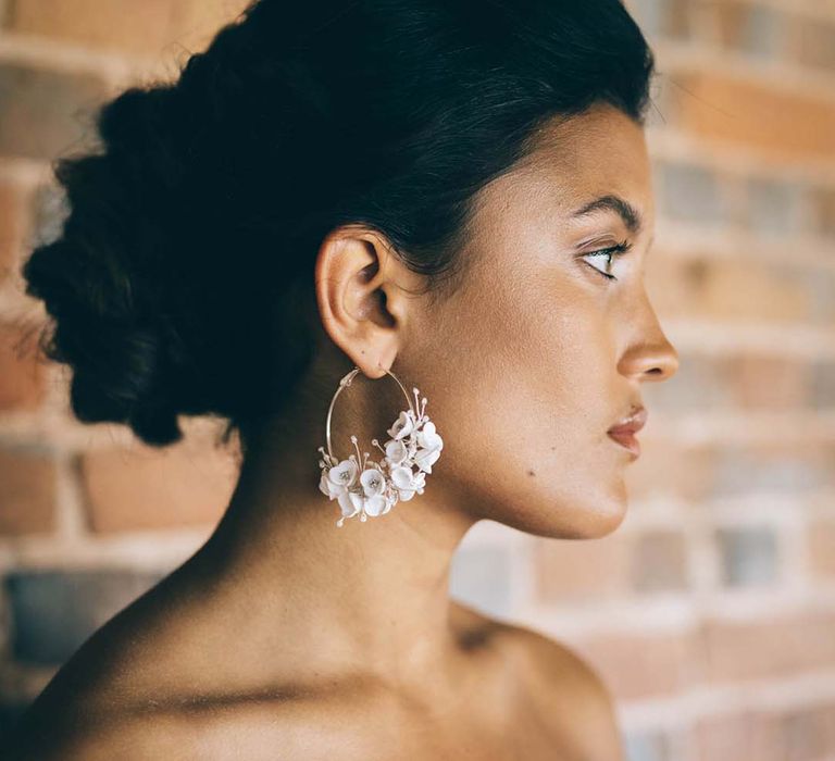 Bride in an off the shoulder wedding dress with flower hoop earrings and pinned bridal updo 