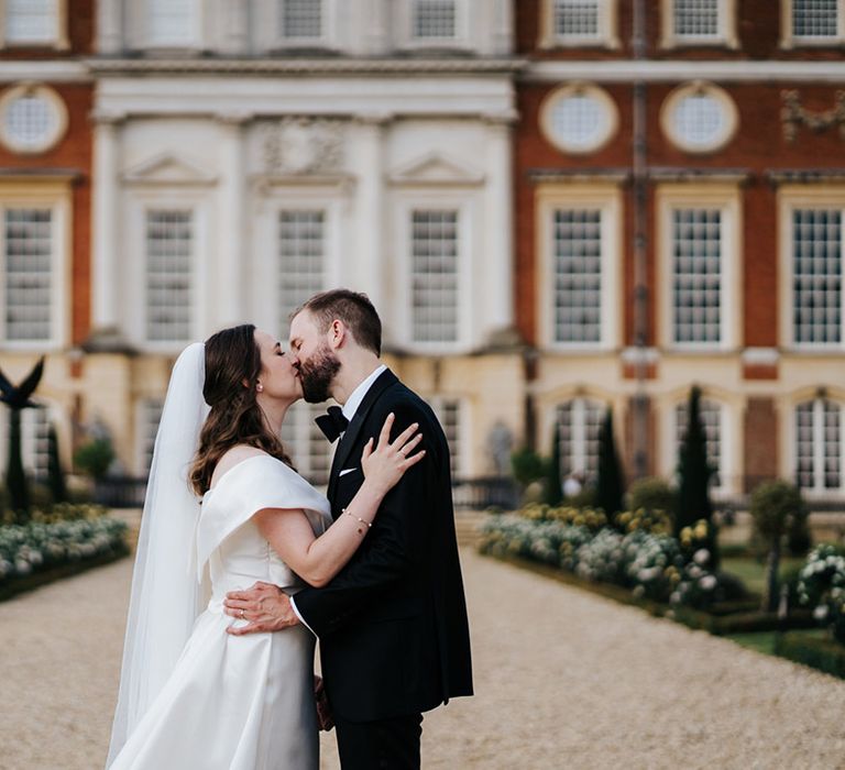 Bride & groom kiss in front of Hampton Court Palace