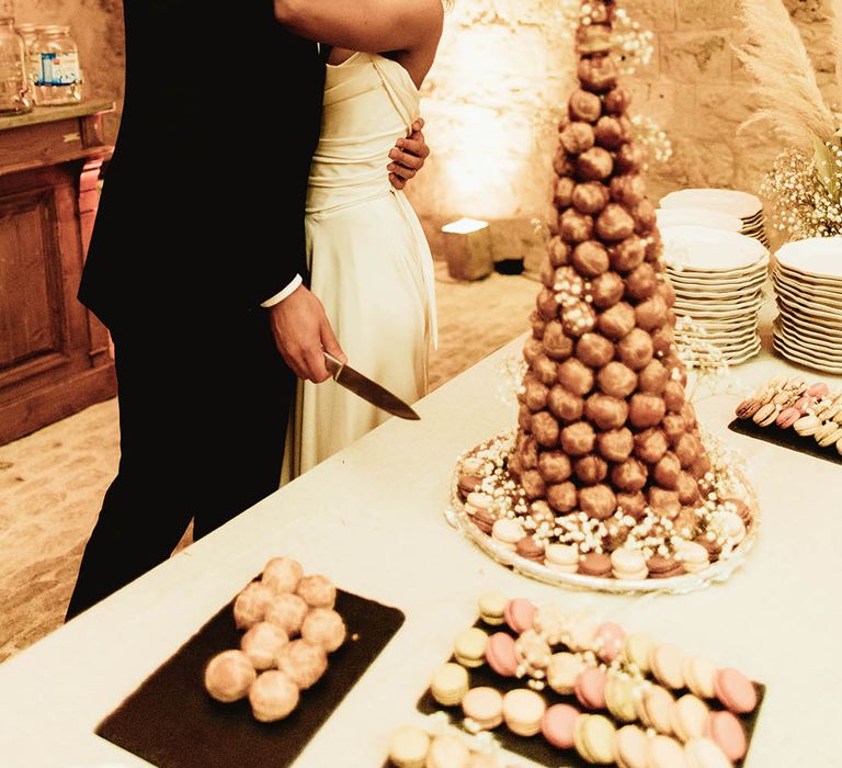 Bride & groom kiss in front croquembouche