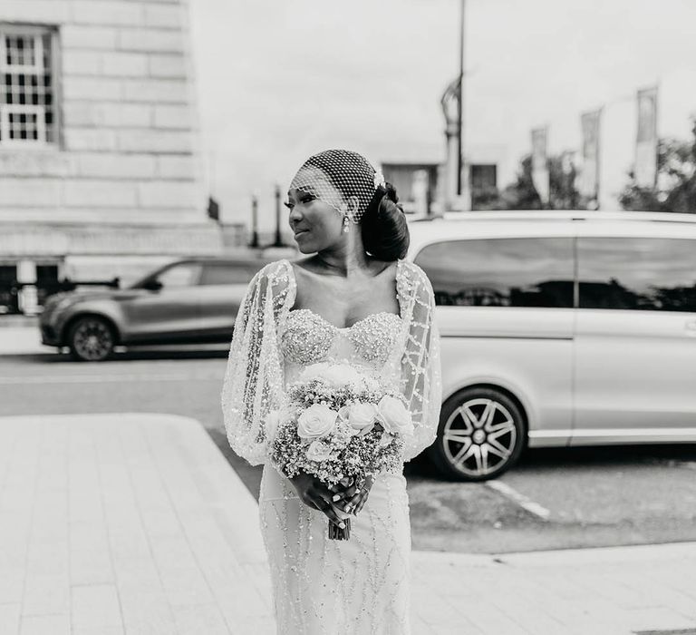 Bride wears beautifully embellished one of a kind wedding gown complete with full sleeves and birdcage veil