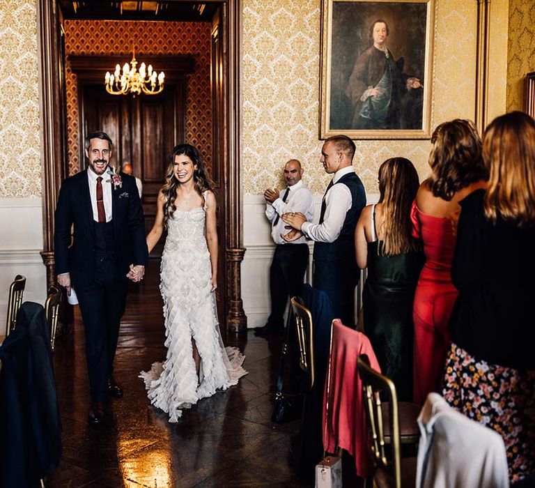 Bride & groom walk into reception at Grittleton House 