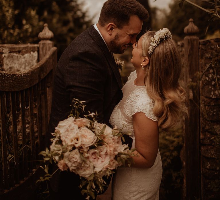 Bride in a lace cap sleeve wedding dress wearing a flower crown and holding a romantic wedding bouquet 