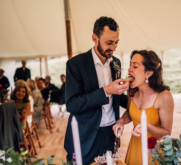 Groom feeds bride wedding cake at reception