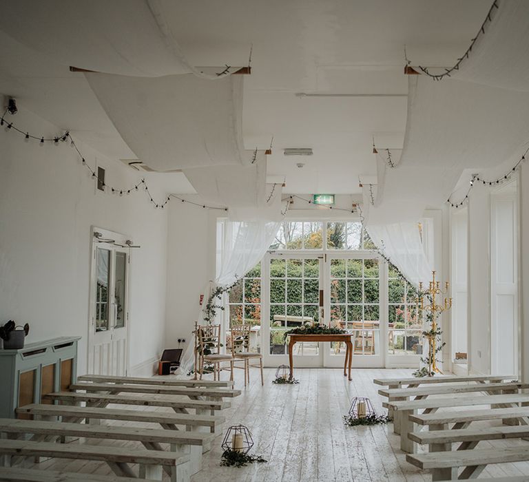 Rustic and classic room featuring white benches with pillar candles and flora decor